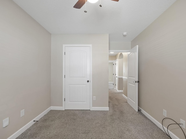 unfurnished bedroom featuring light carpet, a textured ceiling, and ceiling fan