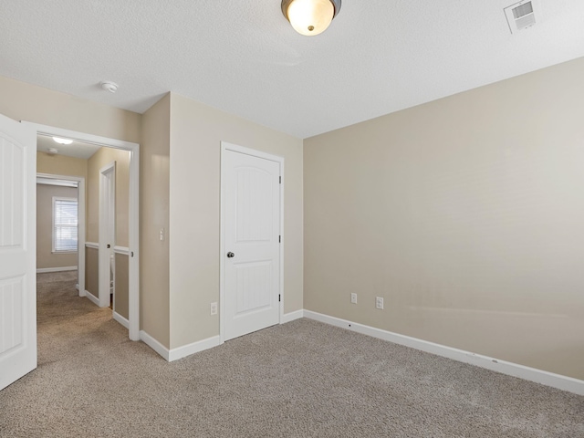 unfurnished bedroom featuring light carpet and a textured ceiling