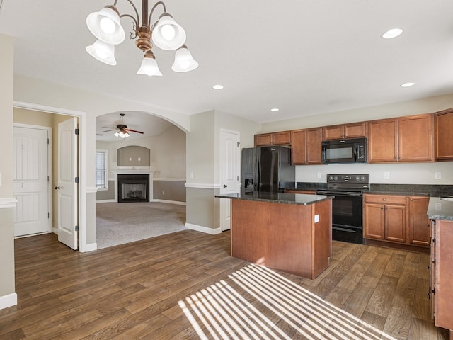 kitchen with dark hardwood / wood-style floors, a kitchen island, dark stone counters, ceiling fan with notable chandelier, and black appliances