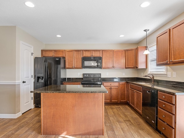 kitchen featuring sink, decorative light fixtures, a kitchen island, light hardwood / wood-style floors, and black appliances