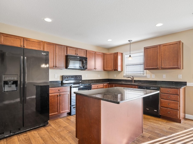 kitchen with light hardwood / wood-style flooring, hanging light fixtures, a kitchen island, and black appliances