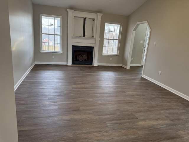 unfurnished living room with a large fireplace, lofted ceiling, and dark hardwood / wood-style flooring