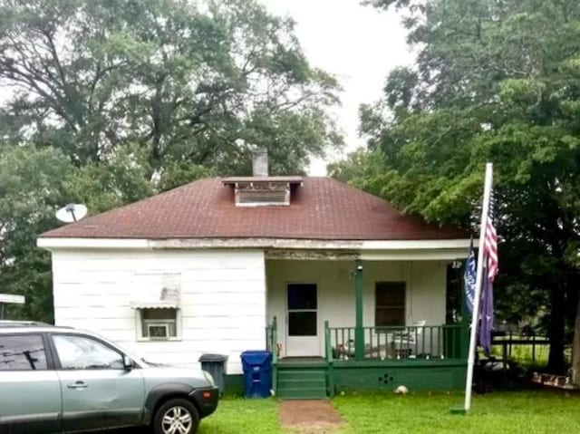 back of property with a yard and covered porch