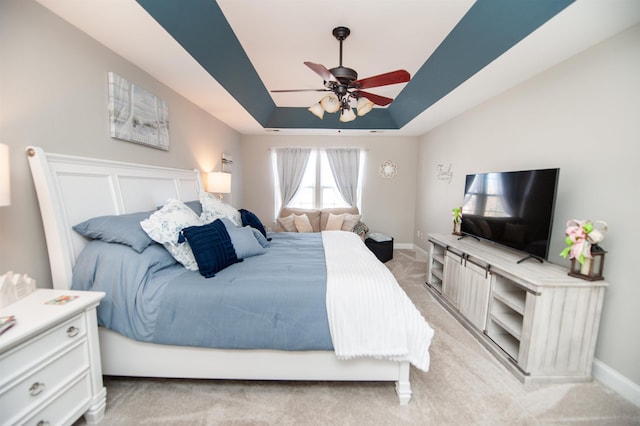 bedroom with light carpet, a raised ceiling, and ceiling fan