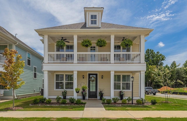 view of front of home with a front lawn, a balcony, ceiling fan, and covered porch