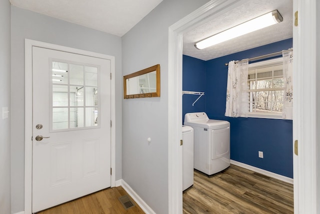 washroom with hardwood / wood-style flooring, a textured ceiling, and washing machine and clothes dryer