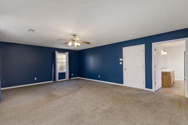 carpeted spare room featuring a textured ceiling and ceiling fan