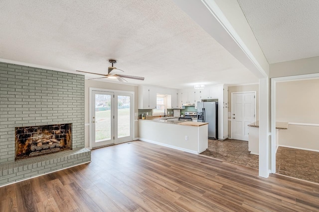 unfurnished living room with dark wood-type flooring, ceiling fan, a fireplace, and a textured ceiling