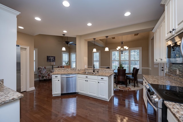 kitchen with sink, appliances with stainless steel finishes, light stone counters, white cabinets, and kitchen peninsula