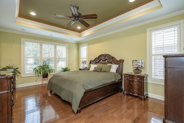 bedroom with hardwood / wood-style floors, ornamental molding, a raised ceiling, and ceiling fan