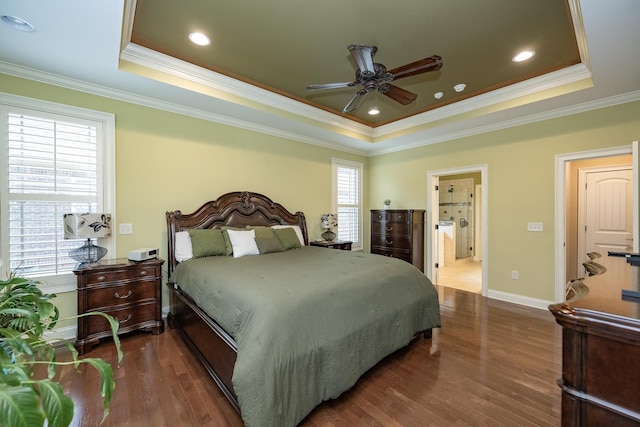 bedroom with ensuite bathroom, ornamental molding, dark hardwood / wood-style floors, a tray ceiling, and ceiling fan