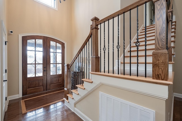 entryway featuring dark hardwood / wood-style flooring, a towering ceiling, and french doors