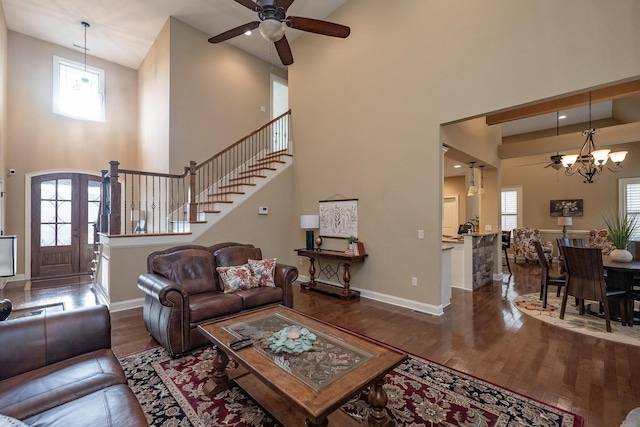 living room with ceiling fan with notable chandelier, dark hardwood / wood-style floors, and a high ceiling