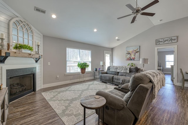 living room with a large fireplace, vaulted ceiling, dark hardwood / wood-style floors, and ceiling fan