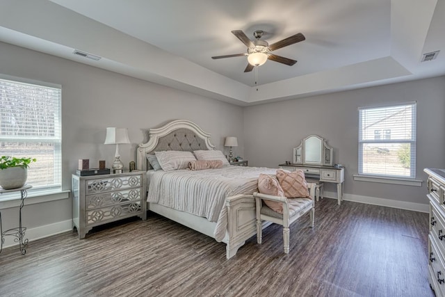 bedroom featuring dark wood-type flooring, ceiling fan, and a tray ceiling