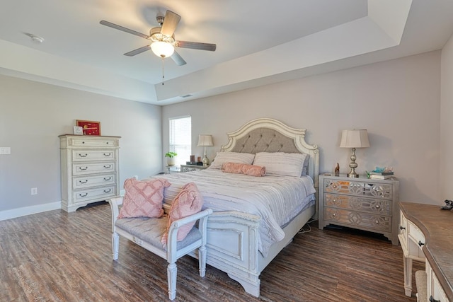 bedroom featuring dark hardwood / wood-style flooring, a tray ceiling, and ceiling fan