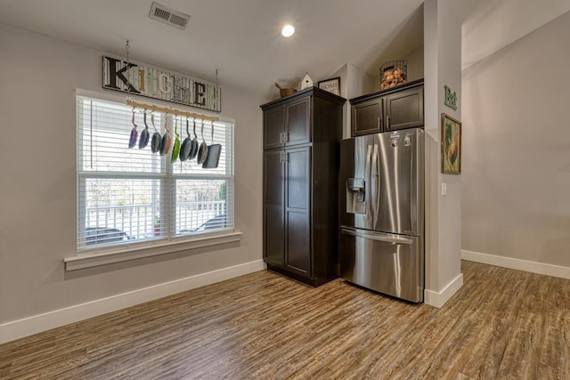 kitchen featuring vaulted ceiling, hardwood / wood-style floors, stainless steel fridge with ice dispenser, and dark brown cabinets