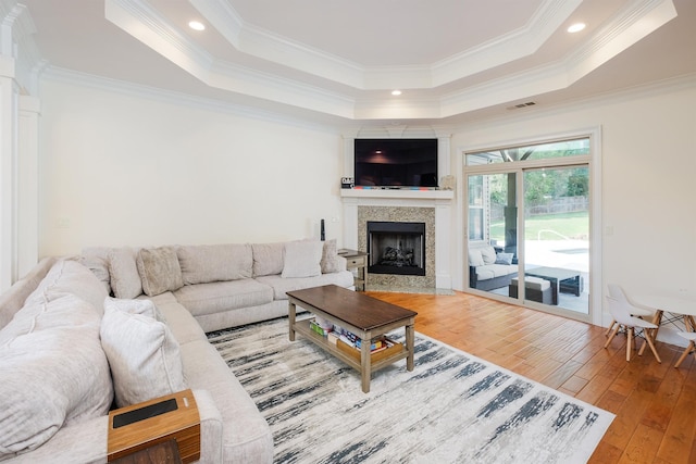 living room featuring crown molding, wood-type flooring, and a raised ceiling