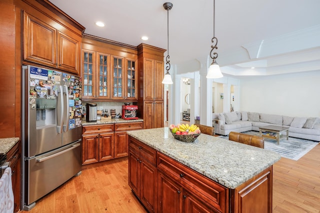 kitchen with stainless steel fridge with ice dispenser, light wood-type flooring, ornamental molding, a kitchen island, and pendant lighting