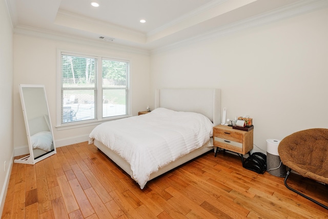 bedroom with a raised ceiling, wood-type flooring, and ornamental molding