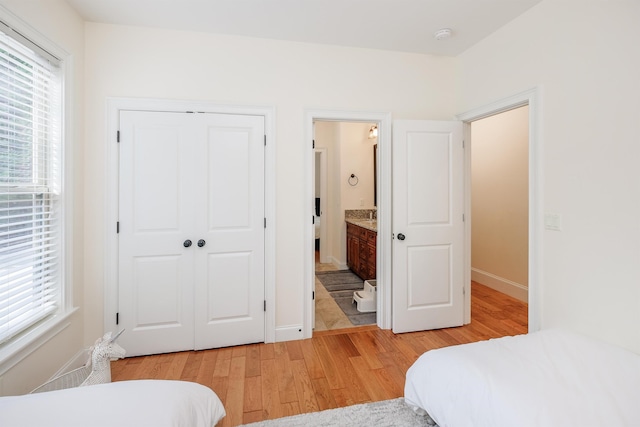 bedroom featuring light hardwood / wood-style flooring, a closet, and ensuite bathroom