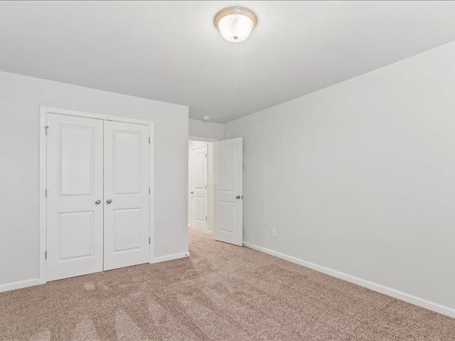 unfurnished bedroom featuring light carpet and a closet