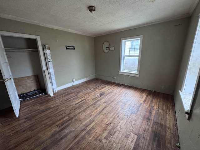 unfurnished bedroom featuring a textured ceiling, dark hardwood / wood-style flooring, and a closet