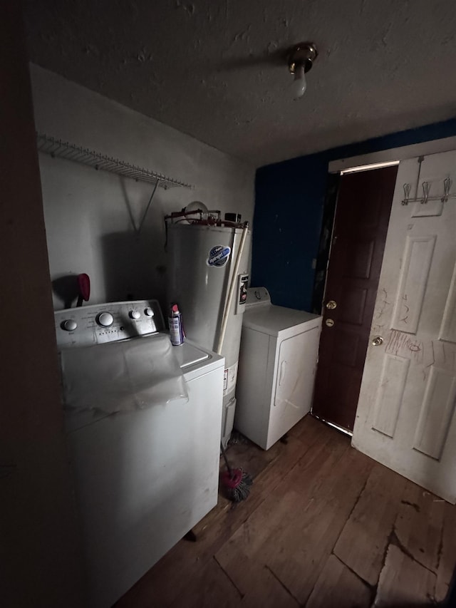 washroom featuring electric water heater, washing machine and clothes dryer, and dark hardwood / wood-style flooring