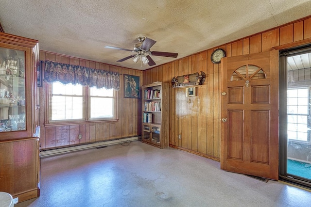 spare room featuring a textured ceiling, a wealth of natural light, a ceiling fan, and a baseboard radiator