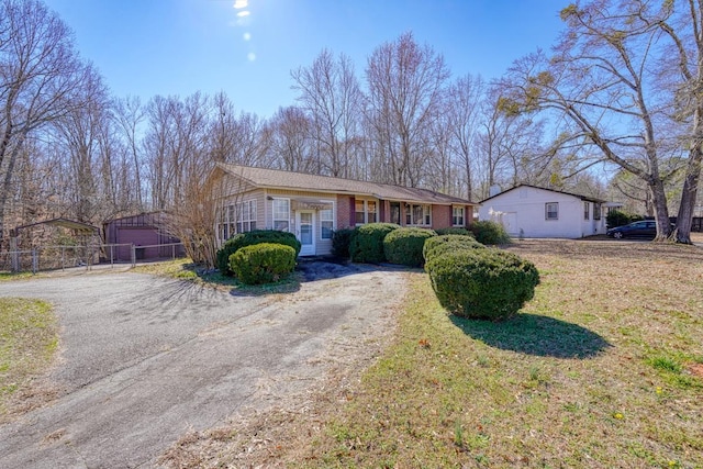 ranch-style house with an outdoor structure, a front yard, driveway, and fence