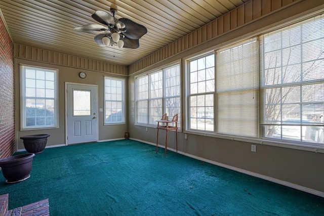 unfurnished sunroom featuring carpet floors and baseboards