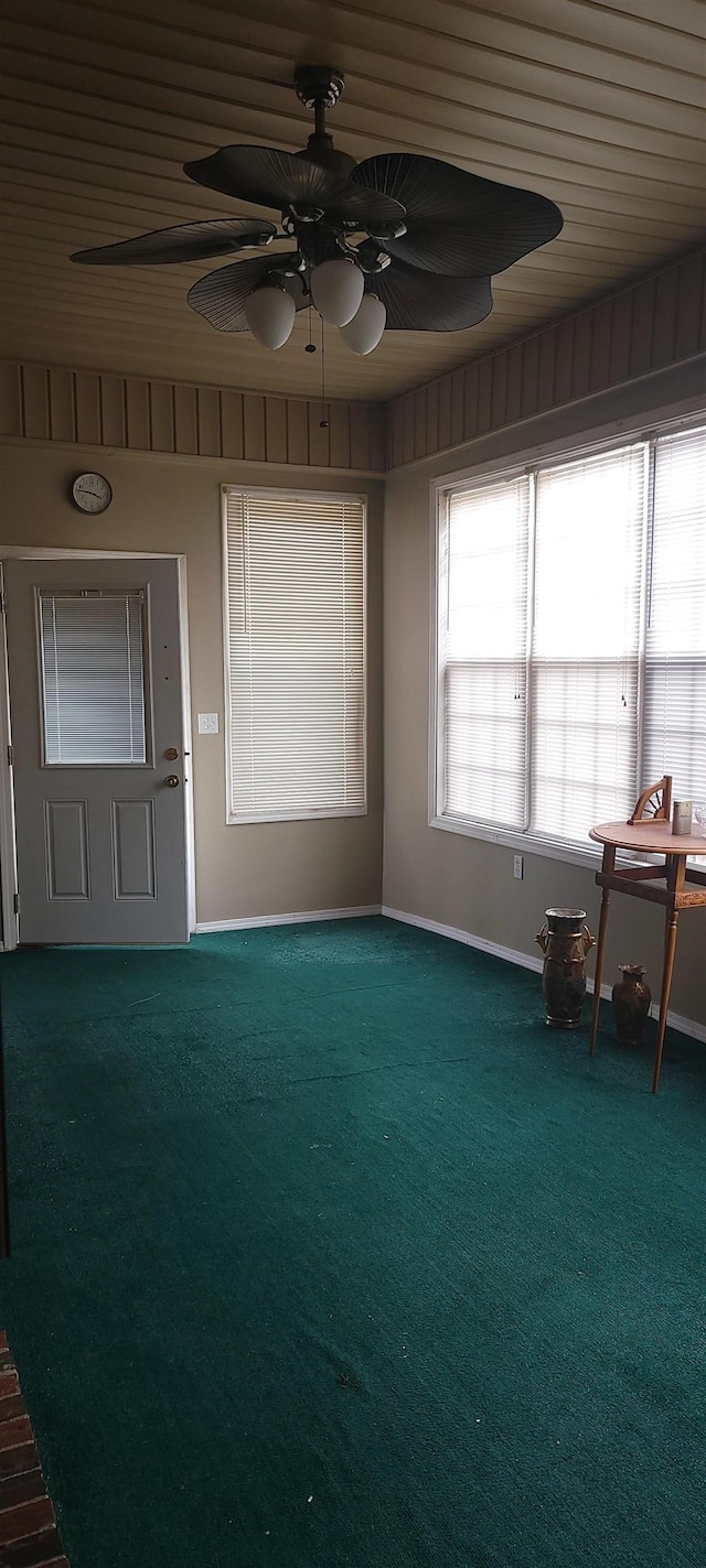 interior space with baseboards, dark colored carpet, and ceiling fan