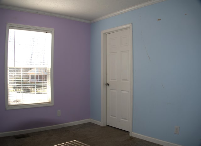 empty room featuring crown molding, a textured ceiling, and dark colored carpet