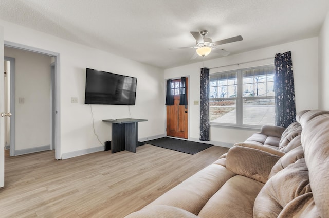 living room featuring ceiling fan, light hardwood / wood-style floors, and a textured ceiling