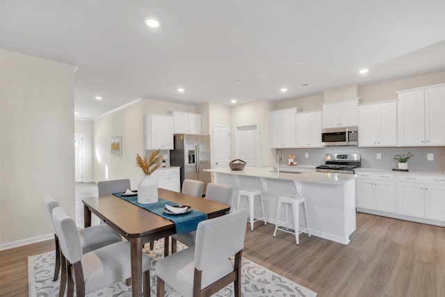 dining area featuring crown molding, sink, and light wood-type flooring