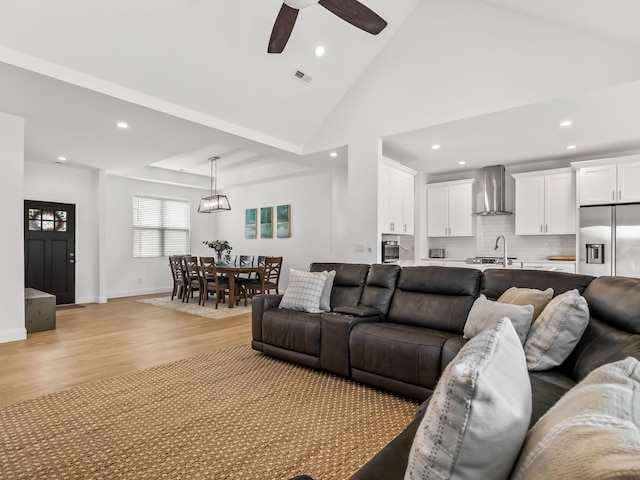 living room featuring ceiling fan, sink, high vaulted ceiling, and light hardwood / wood-style flooring