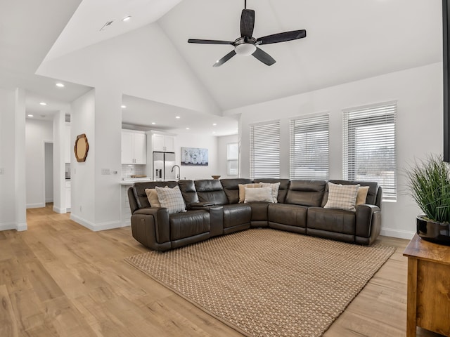 living room featuring sink, high vaulted ceiling, ceiling fan, and light wood-type flooring