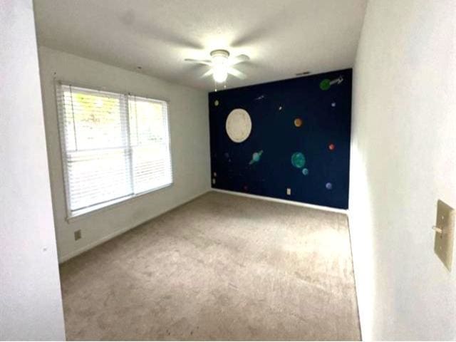 spare room featuring ceiling fan and carpet flooring