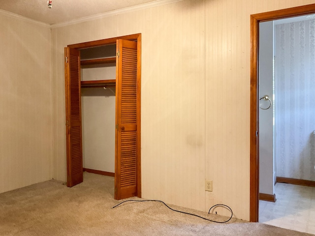 unfurnished bedroom with ornamental molding, light colored carpet, and a closet