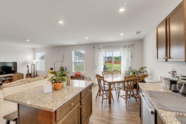 kitchen featuring plenty of natural light, dishwasher, a kitchen island, and light hardwood / wood-style flooring