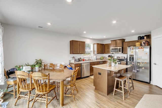 kitchen with sink, light wood-type flooring, a center island, and appliances with stainless steel finishes