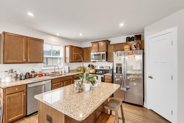 kitchen featuring sink, light hardwood / wood-style flooring, stainless steel appliances, a kitchen breakfast bar, and a kitchen island