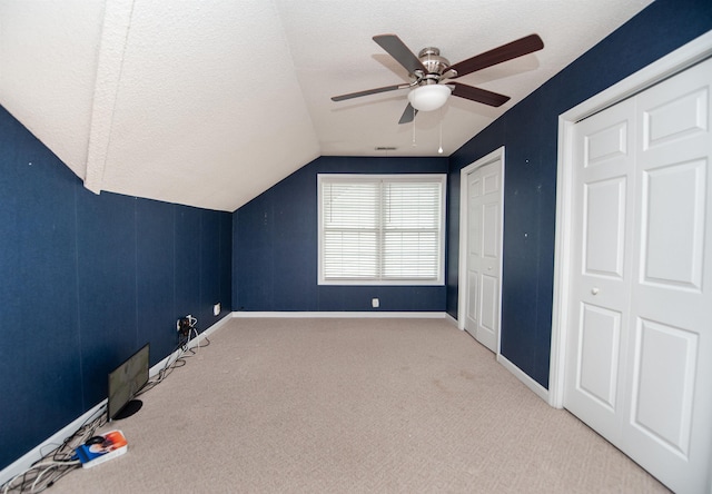 additional living space featuring ceiling fan, lofted ceiling, carpet flooring, and a textured ceiling