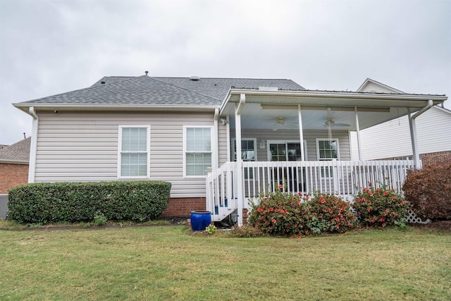 rear view of house featuring ceiling fan and a yard