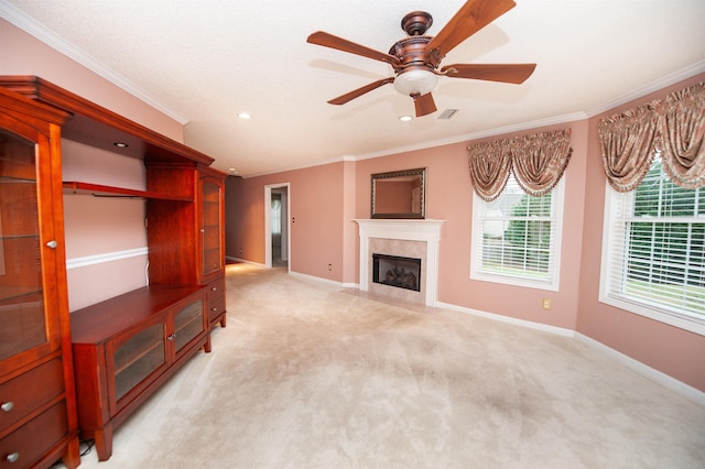 unfurnished living room featuring ceiling fan, ornamental molding, a fireplace, and light carpet