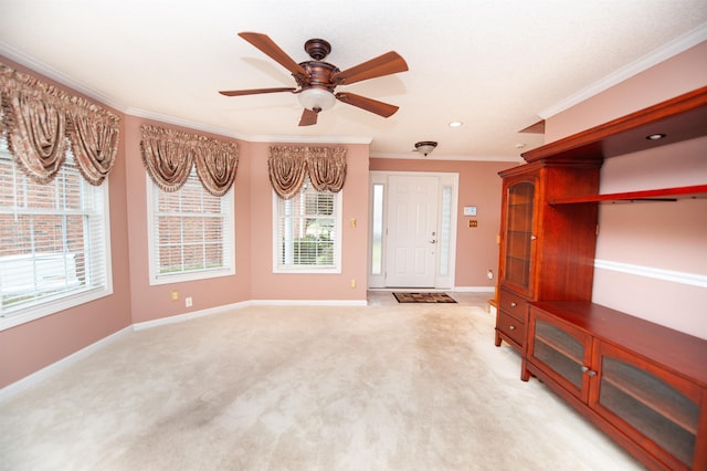 unfurnished living room featuring ceiling fan, light colored carpet, and ornamental molding