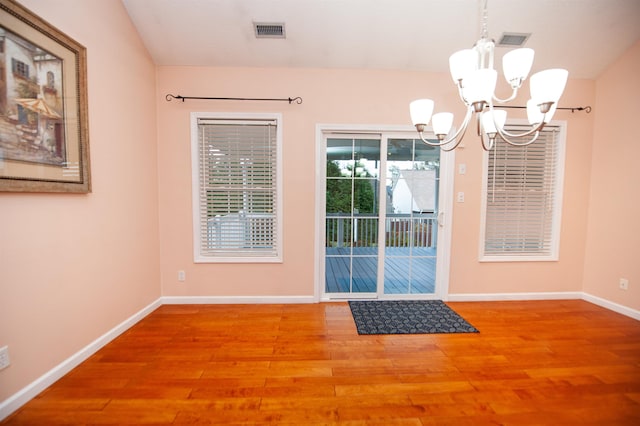 entryway with wood-type flooring and a chandelier