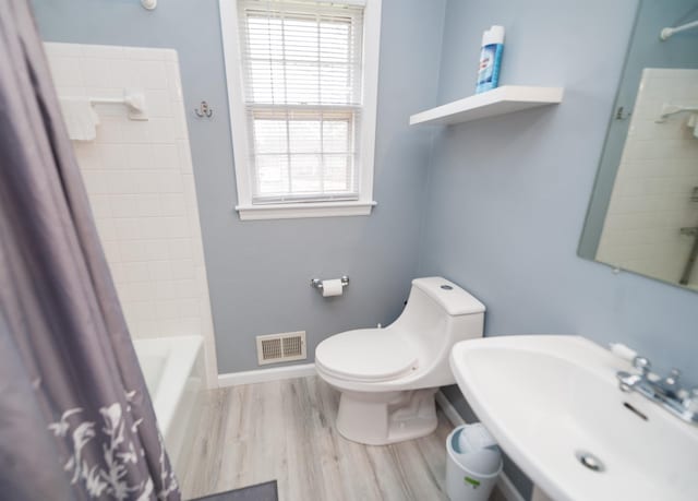 full bathroom with wood-type flooring, toilet, sink, and shower / bath combo with shower curtain