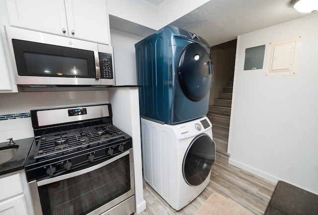 washroom featuring stacked washing maching and dryer, a textured ceiling, and light wood-type flooring