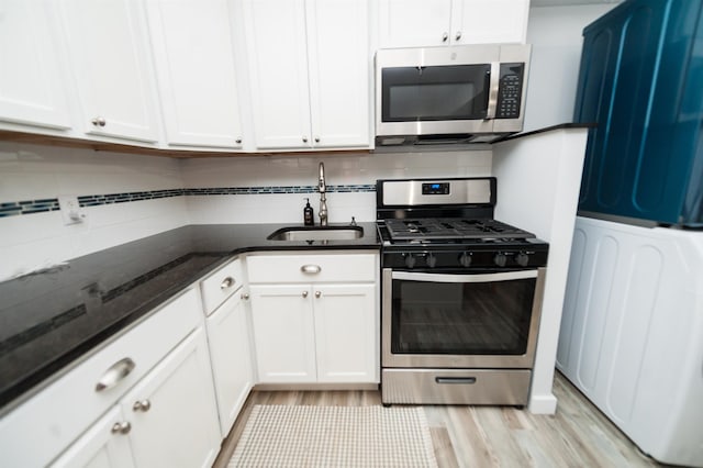 kitchen with sink, dark stone countertops, stainless steel appliances, tasteful backsplash, and white cabinets